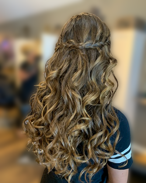 Long brunette curls styled half up with a braid at Maison de Cheveux.