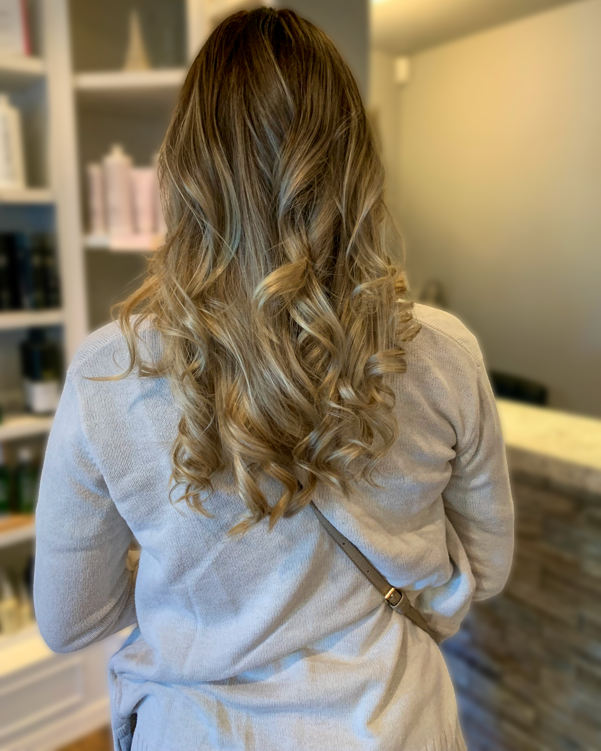 Long bronde hair with dimensional highlights and a curled finish at Maison de Cheveux.