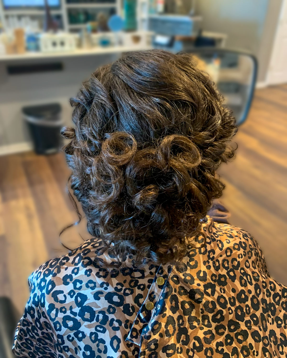 Dark brunette hair arranged in a curled updo at Maison de Cheveux.