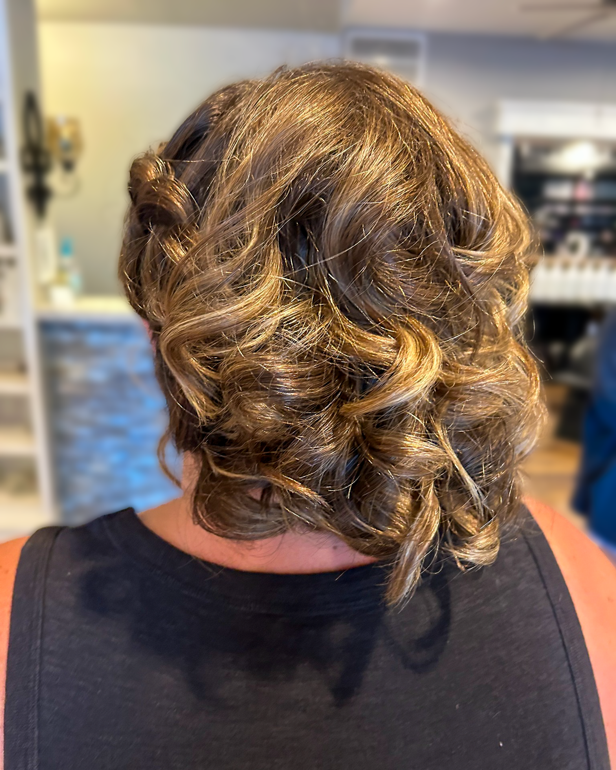 Short brunette hair styled in soft formal curls at Maison de Cheveux.