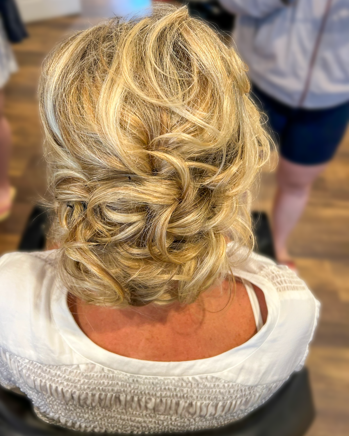 Blonde hair arranged in a textured updo at Maison de Cheveux.