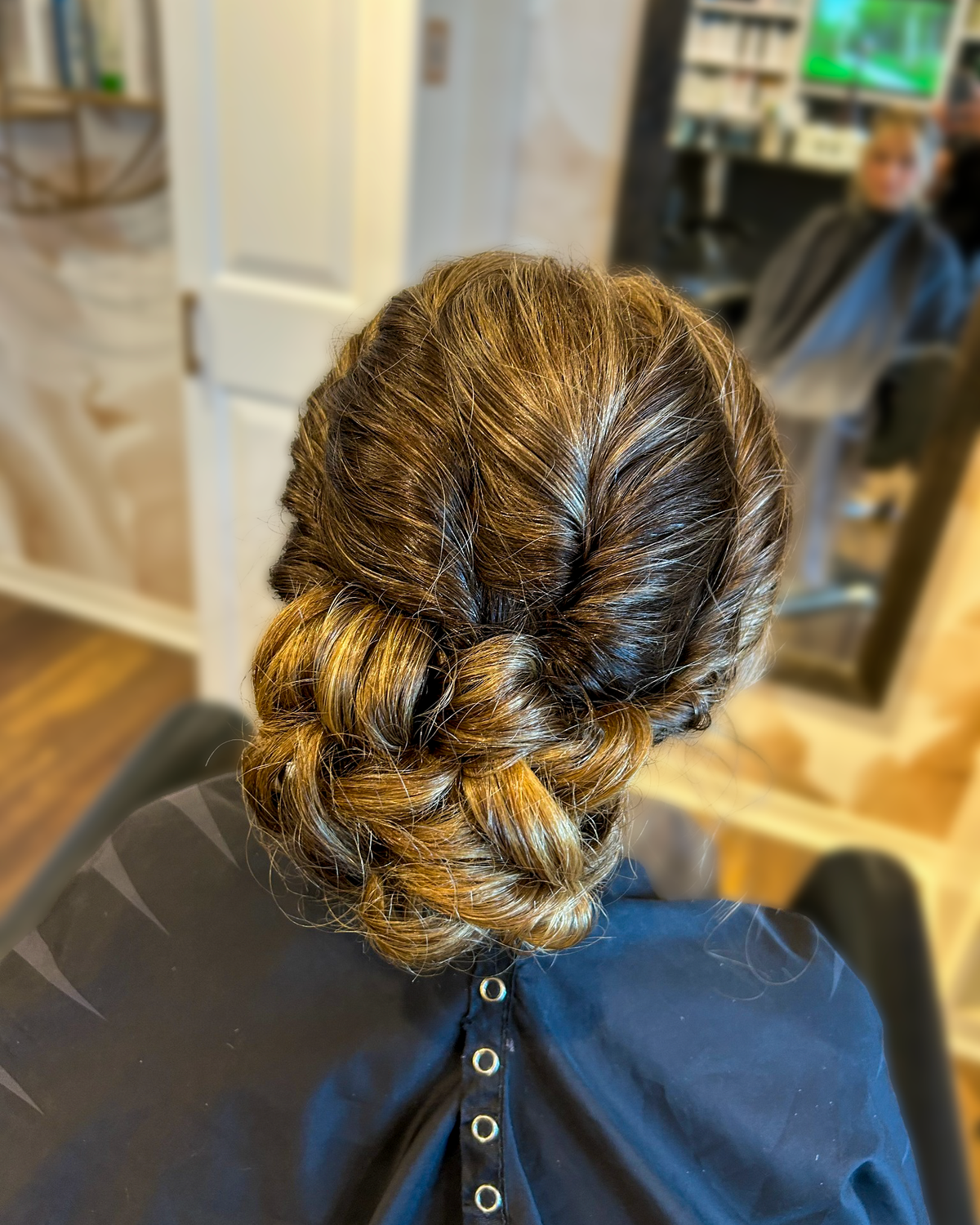 Dimensional brunette hair in a low braided bun at Maison de Cheveux.