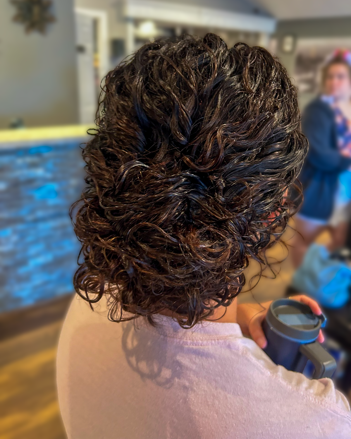 Dark brunette hair styled in a textured curly updo at Maison de Cheveux.