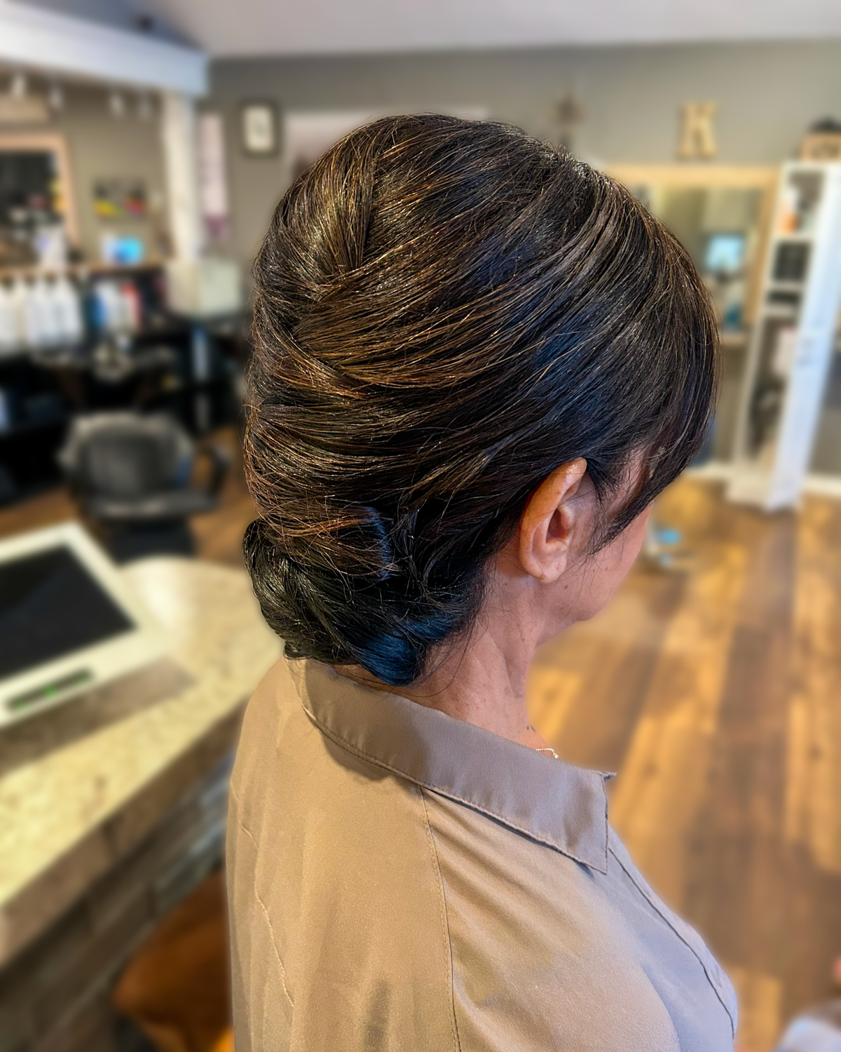 Dark brunette hair styled in a sleek low chignon at Maison de Cheveux.